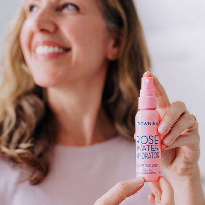 Kvinna som sprayar Frownies Rose Water Hydrator i ansiktet – återfuktning och aktivering av ansiktsplåster.
