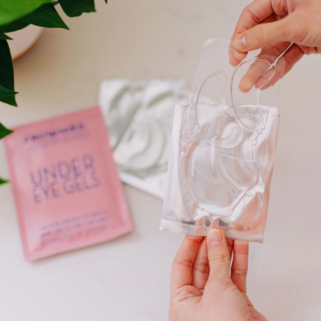 Hand som håller upp Frownies Under Eye Gels ur förpackningen – lätt att applicera.