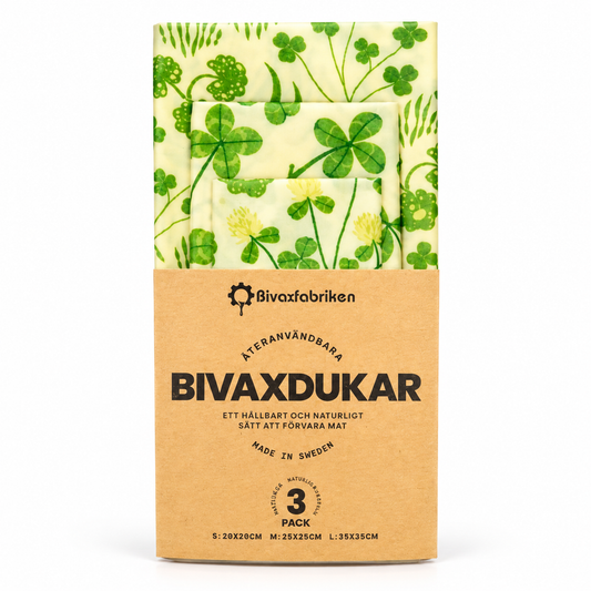 Bivaxfabriken återanvändbara bivaxdukar i tre storlekar med grönt klöver- och bladmönster, i en naturfärgad pappersförpackning mot vit bakgrund.