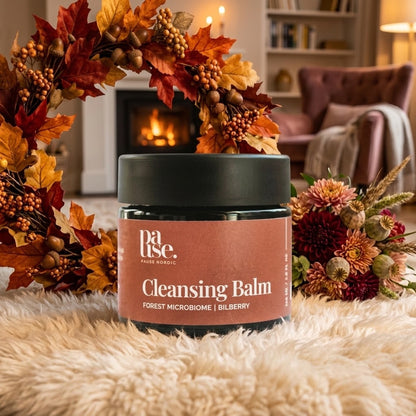 Cleansing Balm från Pause Nordic i en varm höstmiljö med brasa, höstlöv och blommor.