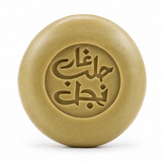 Rund olivfärgad Aleppotvål från Najel med präglad arabisk text, fotograferad rakt framifrån mot vit bakgrund.